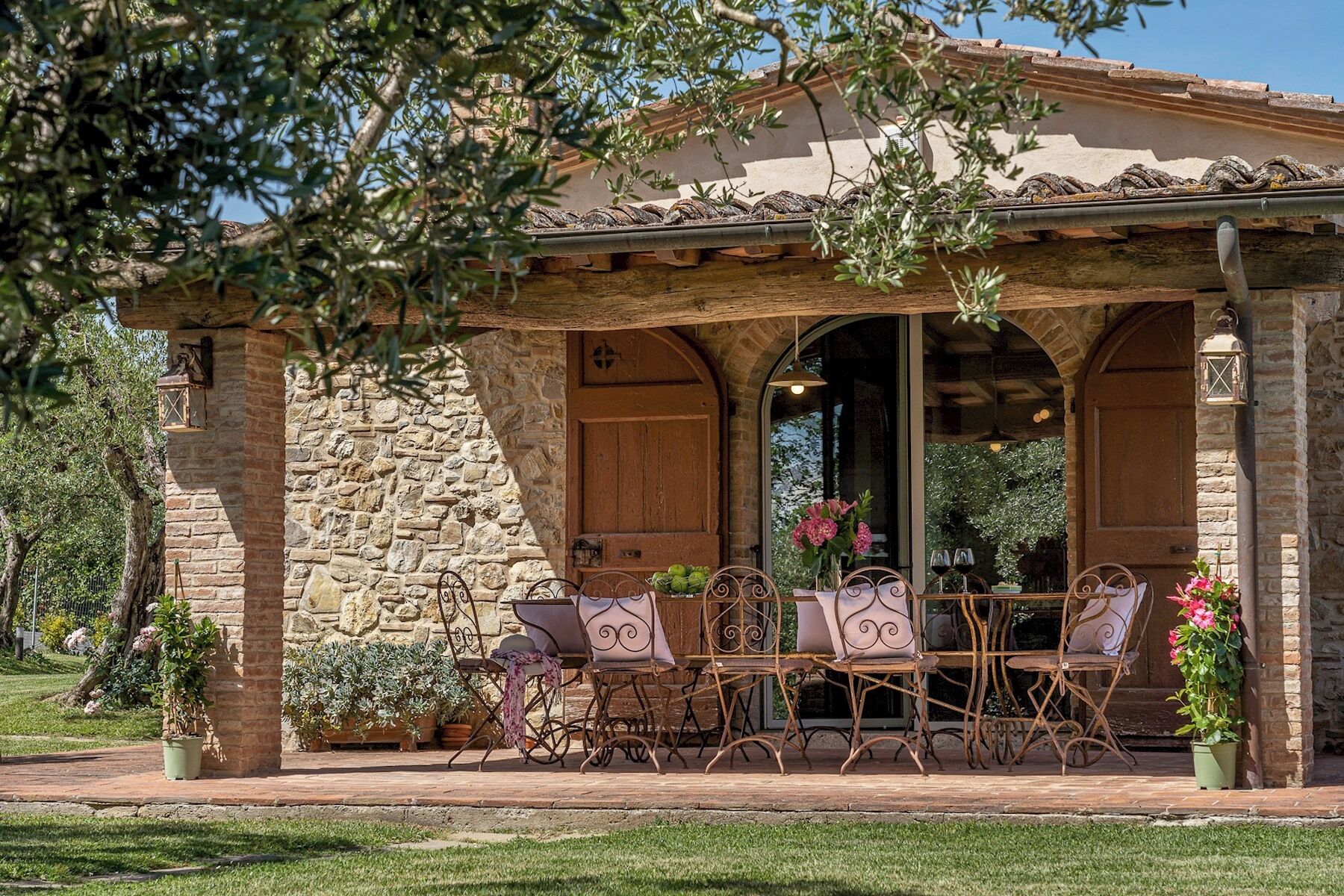 A stone building with a covered patio, outdoor seating, and potted plants.
