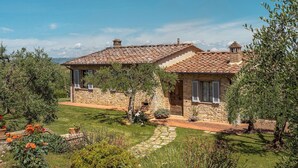 Una casa de piedra con techo de tejas, rodeada por un jardín bien cuidado con diversas plantas y un sendero de piedra.