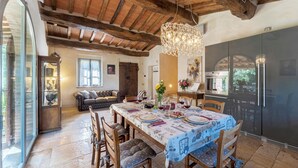 Un comedor con una mesa de madera dispuesta para cuatro, rodeada de sillas con cojines azules con lunares.