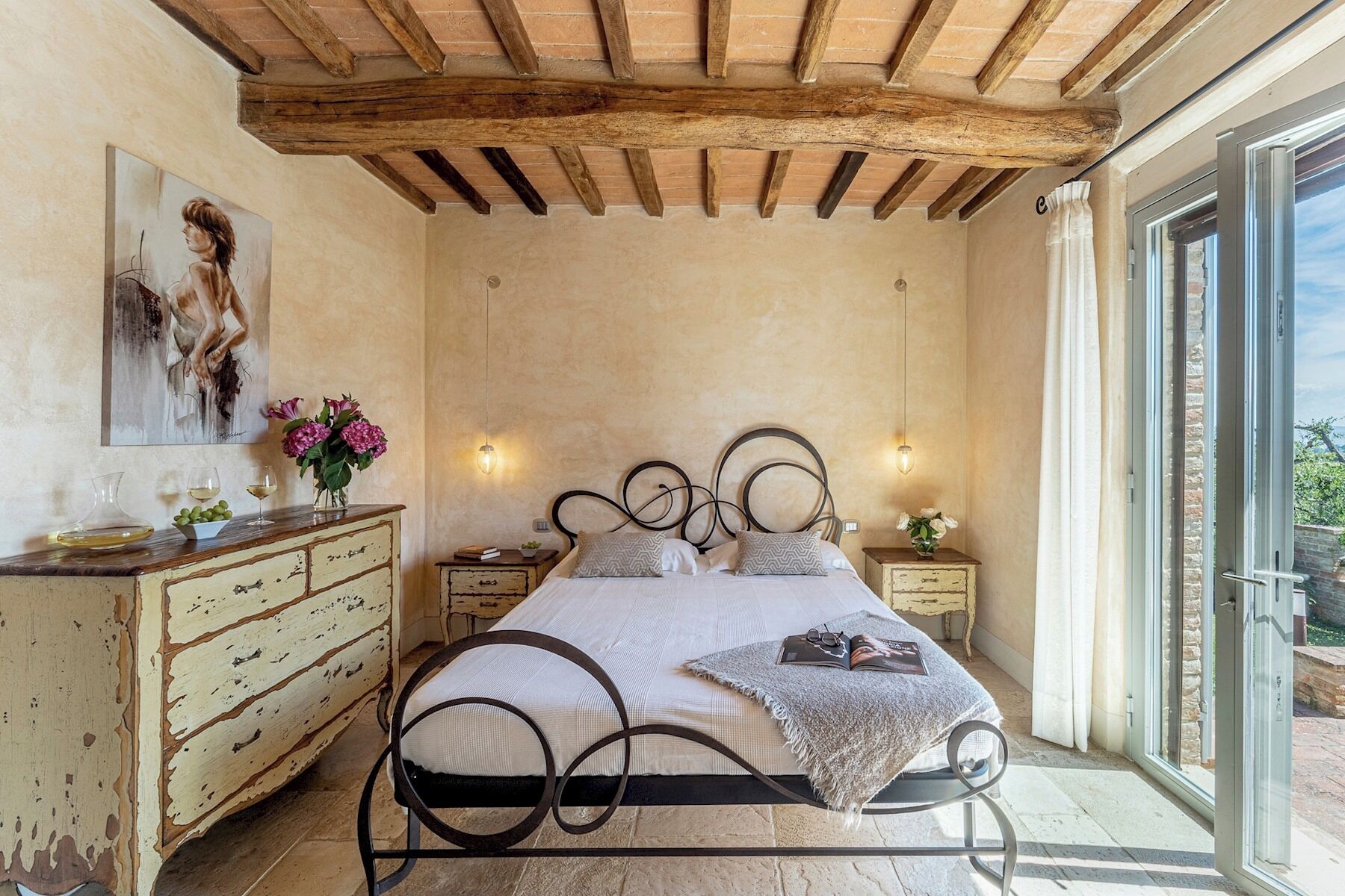 Une chambre à coucher avec un lit, une tête de lit en bois, des tables de chevet, une commode et un tableau au mur.