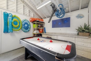 An indoor ice hockey rink with a pool table, inflatable toys, and a painting of a fish on the wall. - Posh spacious pool house in the Heights. (Tampa)