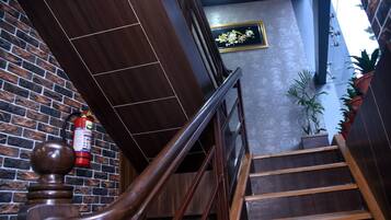 A wooden staircase with a handrail, a fire extinguisher, and a brick wall.
