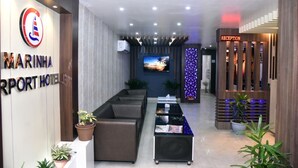A modern reception area with a reception desk, seating area, and a TV screen. - Marinha Airport Hotel (Kathmandu)