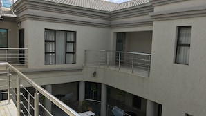 A two-story building with a balcony, a covered outdoor seating area, and a small garden. - Salerato Boutique Hotel (Gaborone)