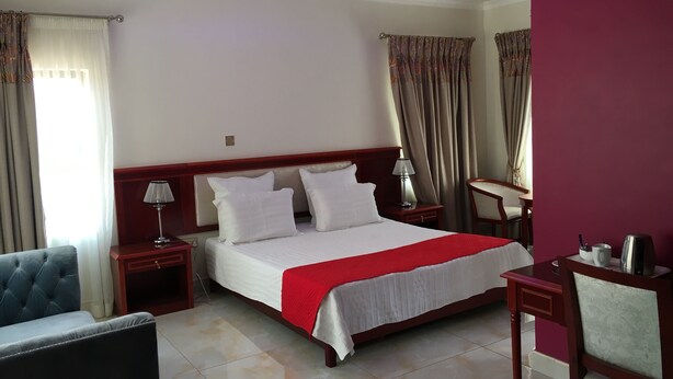A hotel room with a bed, a chair, a desk, and a lamp. - Salerato Boutique Hotel (Gaborone)