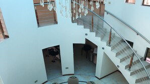 A spacious atrium with a central round table and seating, a staircase, and a chandelier. - Salerato Boutique Hotel (Gaborone)