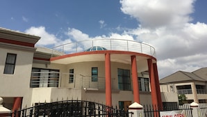 A building with a circular structure, large windows, and a red and white color scheme. - Salerato Boutique Hotel (Gaborone)