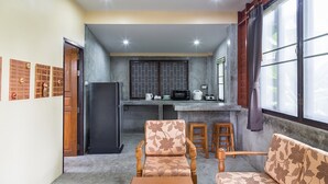 A compact living space with a kitchenette, seating area, and a large window.