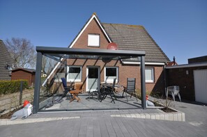 Una casa moderna con un patio envidriado, fachada de ladrillo y techo inclinado.