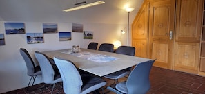 A dining area with a table set for six, surrounded by chairs, a lamp, and wall-mounted artwork.