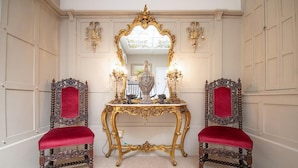 A room with two ornate chairs, a gold-framed mirror, and a table with a red cloth. - Plas Maenan Country House (Llanrwst)