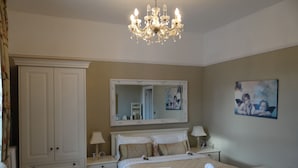A bedroom with a large bed, a wardrobe, a mirror, and a chandelier. - Plas Maenan Country House (Llanrwst)