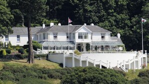 A large, white, two-story house with a balcony and a flag. - Plas Maenan Country House (Llanrwst)