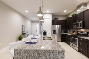 A modern kitchen with granite countertops, stainless steel appliances, and dark cabinetry.