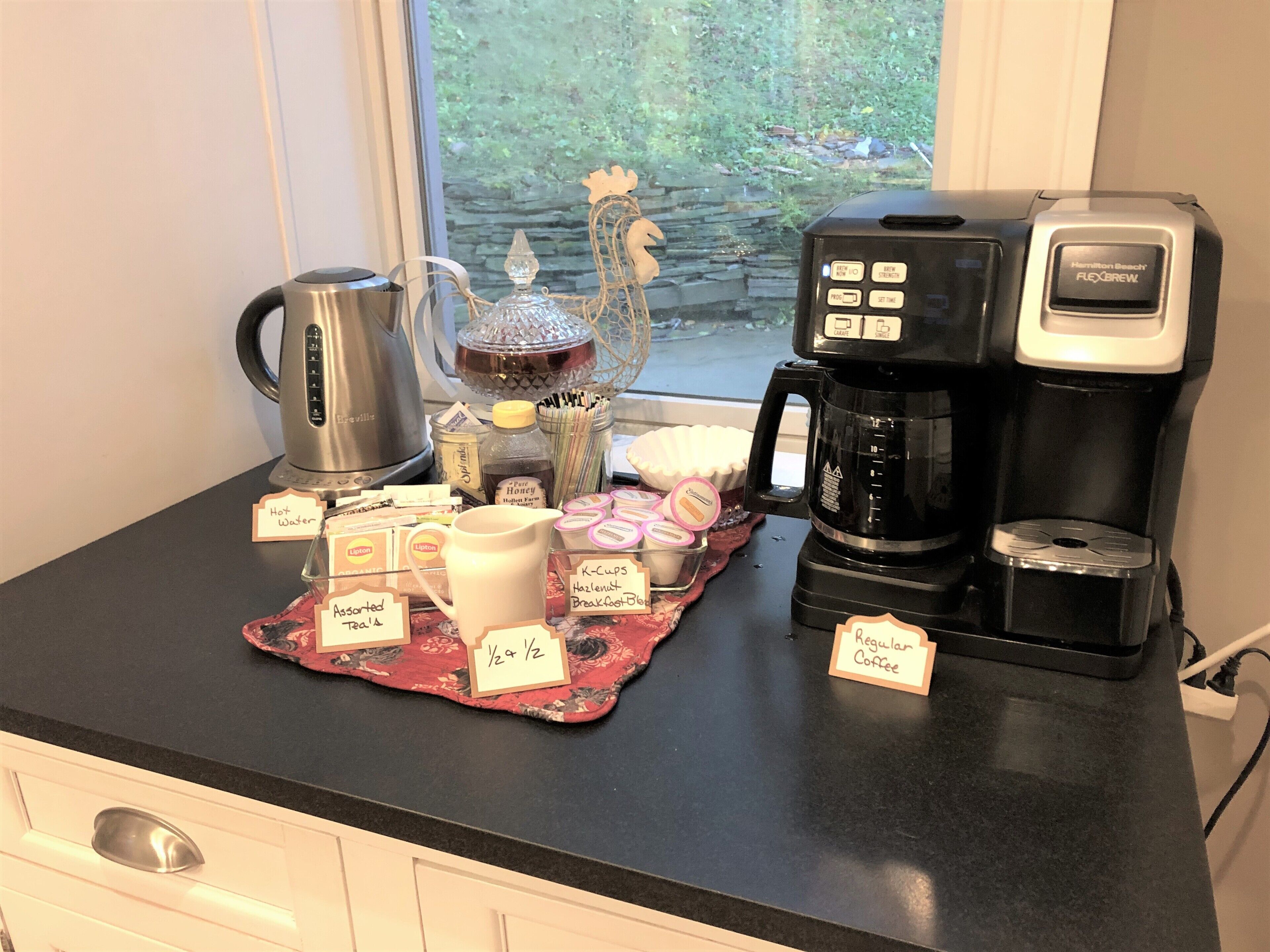 A kitchen counter with a coffee maker, a kettle, and various coffee pods and tea bags.