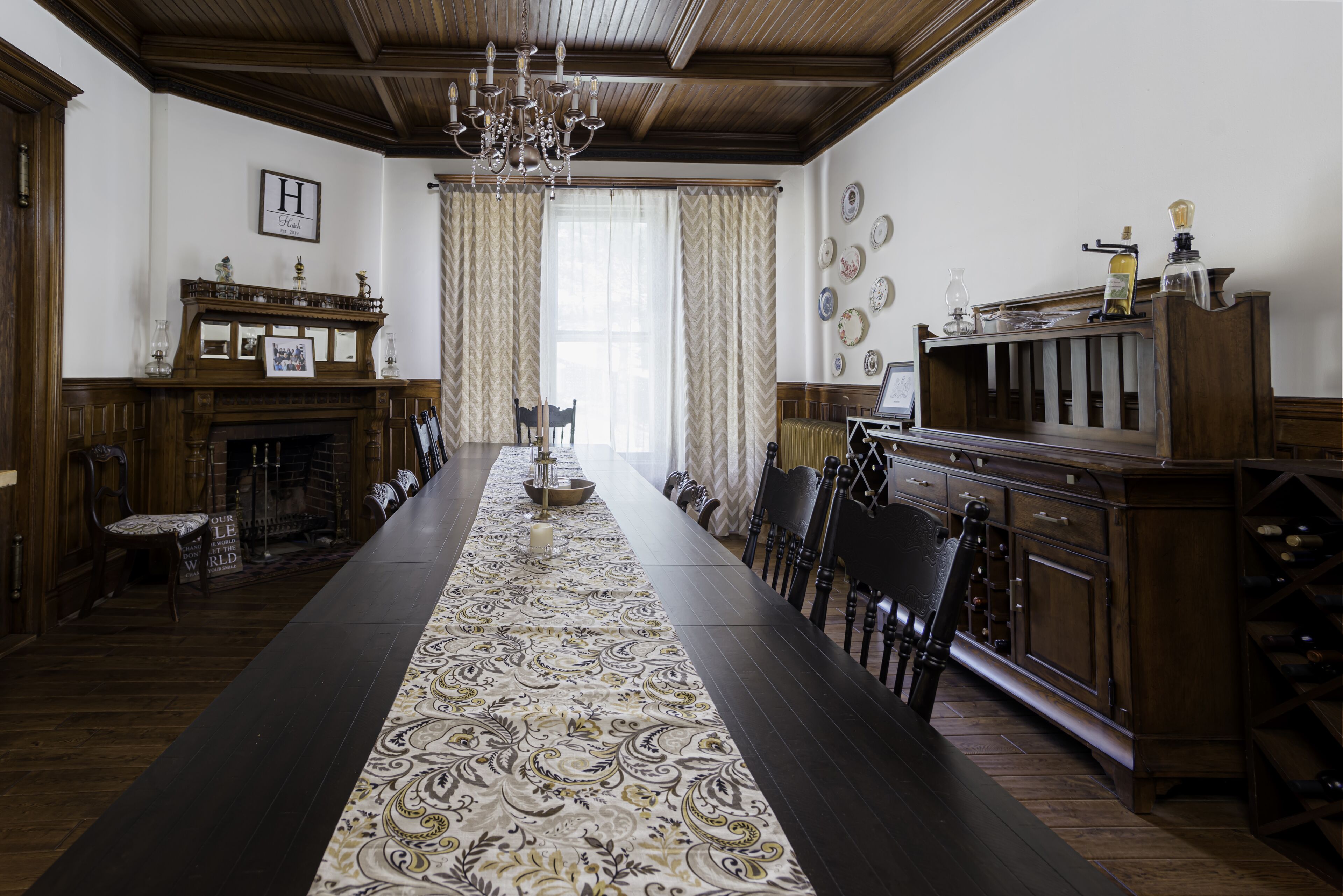 A formal dining room with a long table, chairs, a fireplace, and a chandelier.