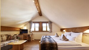 Een knus, goed verlichte kamer met een bed, een bank, een kleine tafel en een televisie.