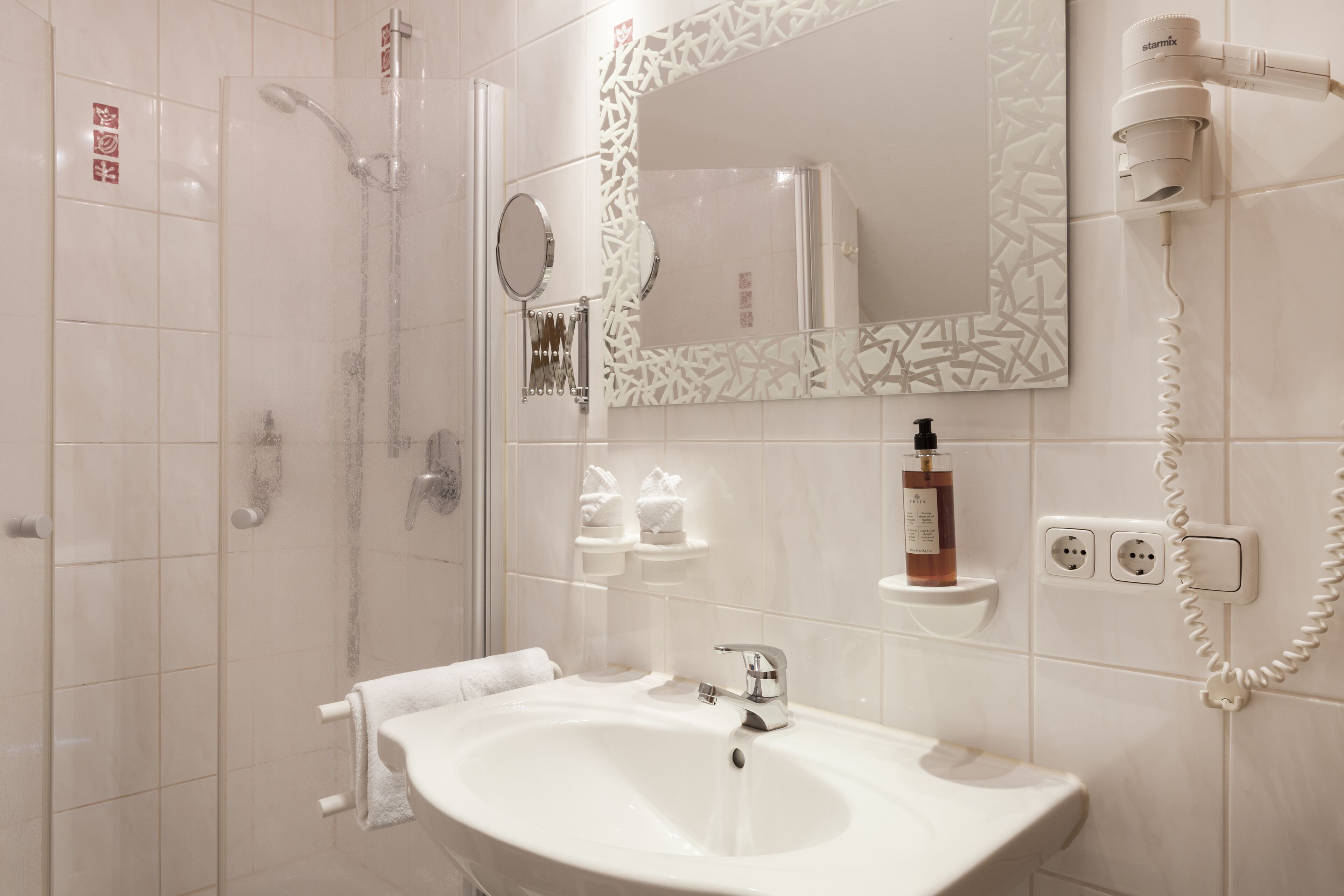 Ein modernes Badezimmer mit Dusche, Waschbecken und Fön.