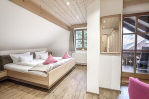 Une chambre avec un lit en bois, une fenêtre donnant sur un immeuble et une chaise.