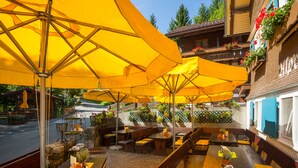 Een terras met gele parasols, houten banken en tafels.