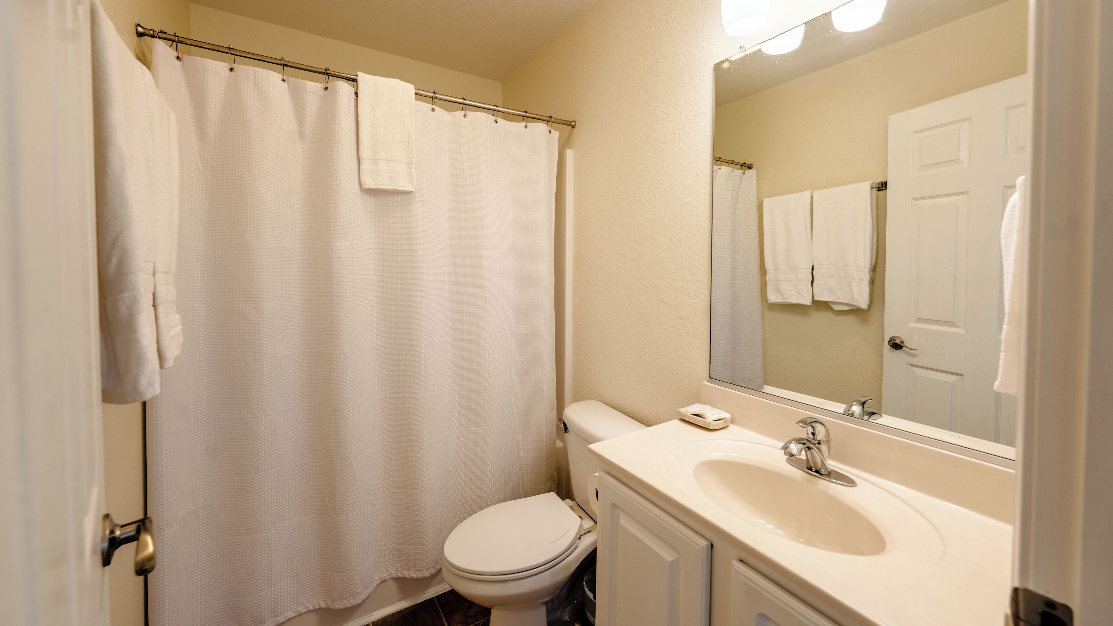 A bathroom with a toilet, sink, and shower curtain.