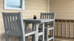 Relax in a serene outdoor seating area with a table and two chairs, surrounded by lush greenery and a view.