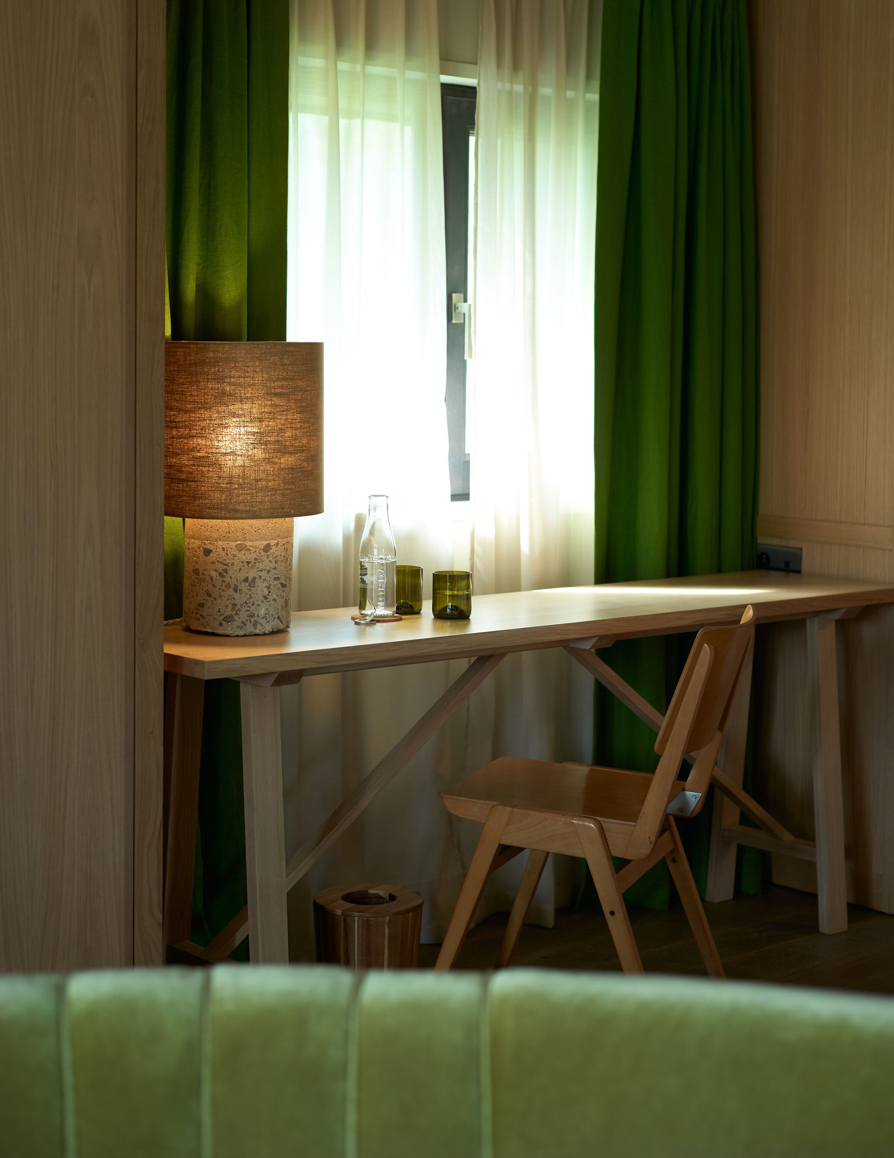 A wooden table with a lamp, a bottle, and a glass.