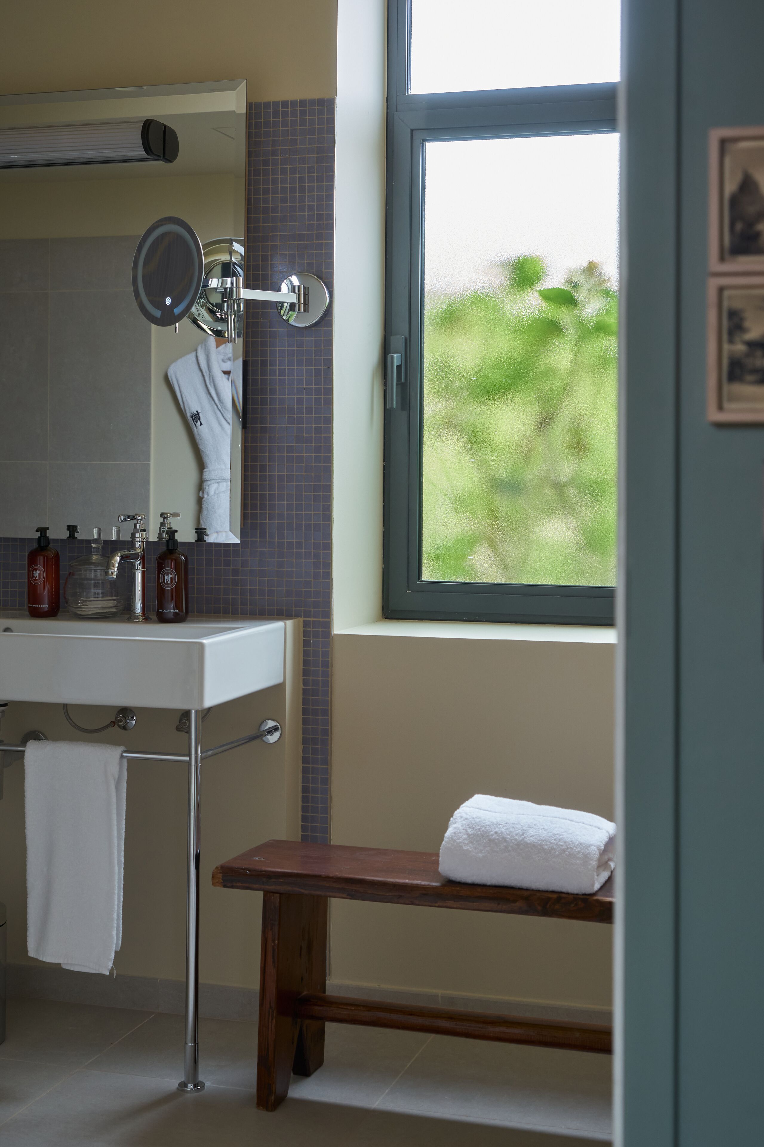 Un baño con lavamanos, espejo y ventana.