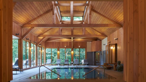 Ein Holzinnenraum mit Pool, großen Fenstern und hoher Decke.
