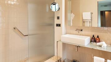 A modern bathroom with a glass shower enclosure, a white sink, and a vanity with toiletries.