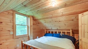 A wooden cabin bedroom with a bed, a window, and a door. - Near Snowmobiling: Secluded Harmony Cabin w/ Deck! (Harmony)