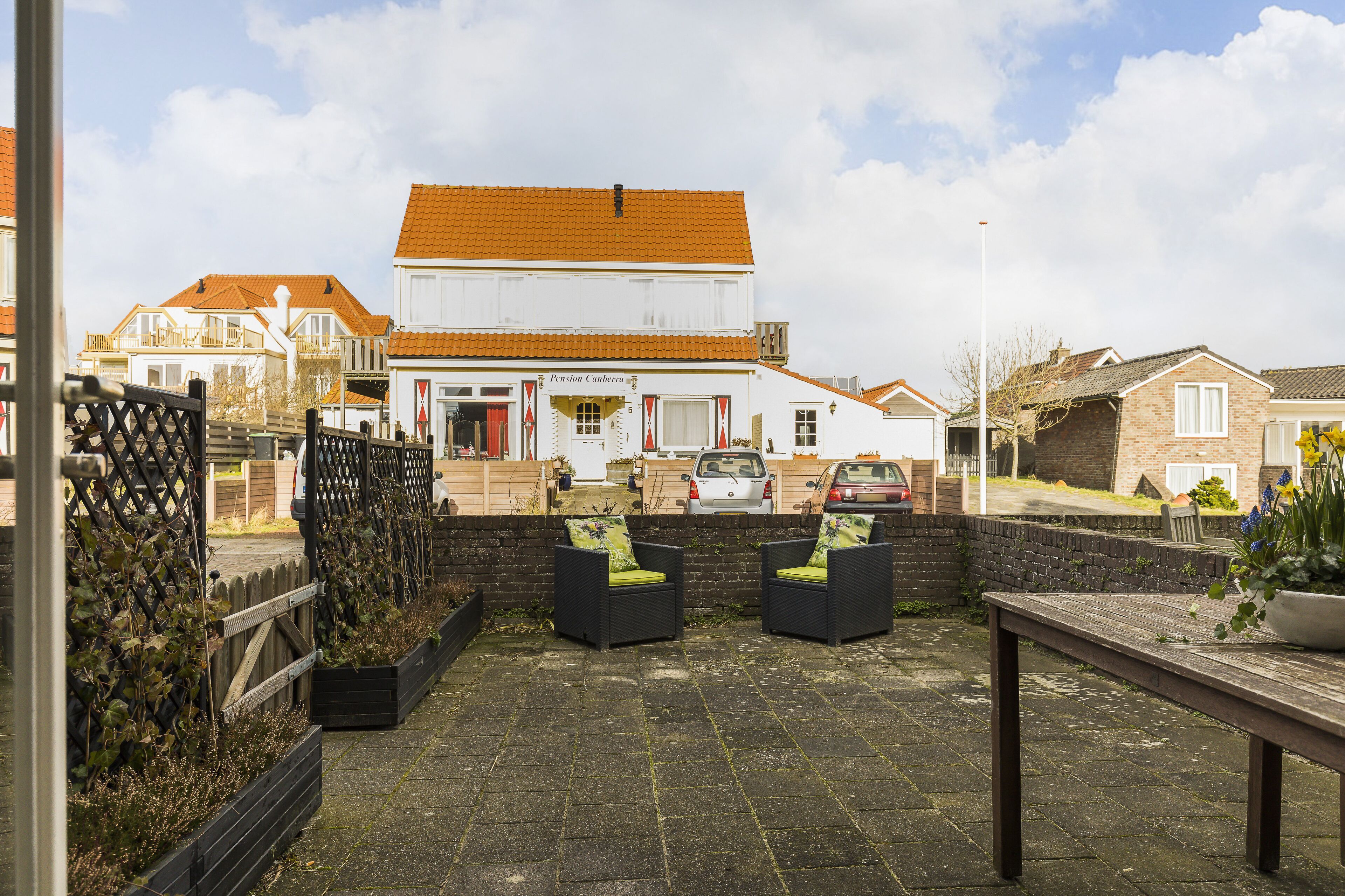 A patio area with outdoor seating and a view of a building with a tiled roof.