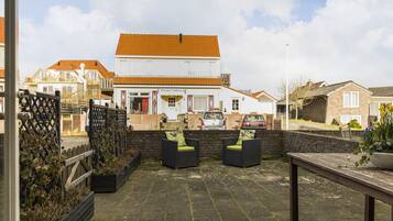 A patio area with outdoor seating and a view of a building with a tiled roof.