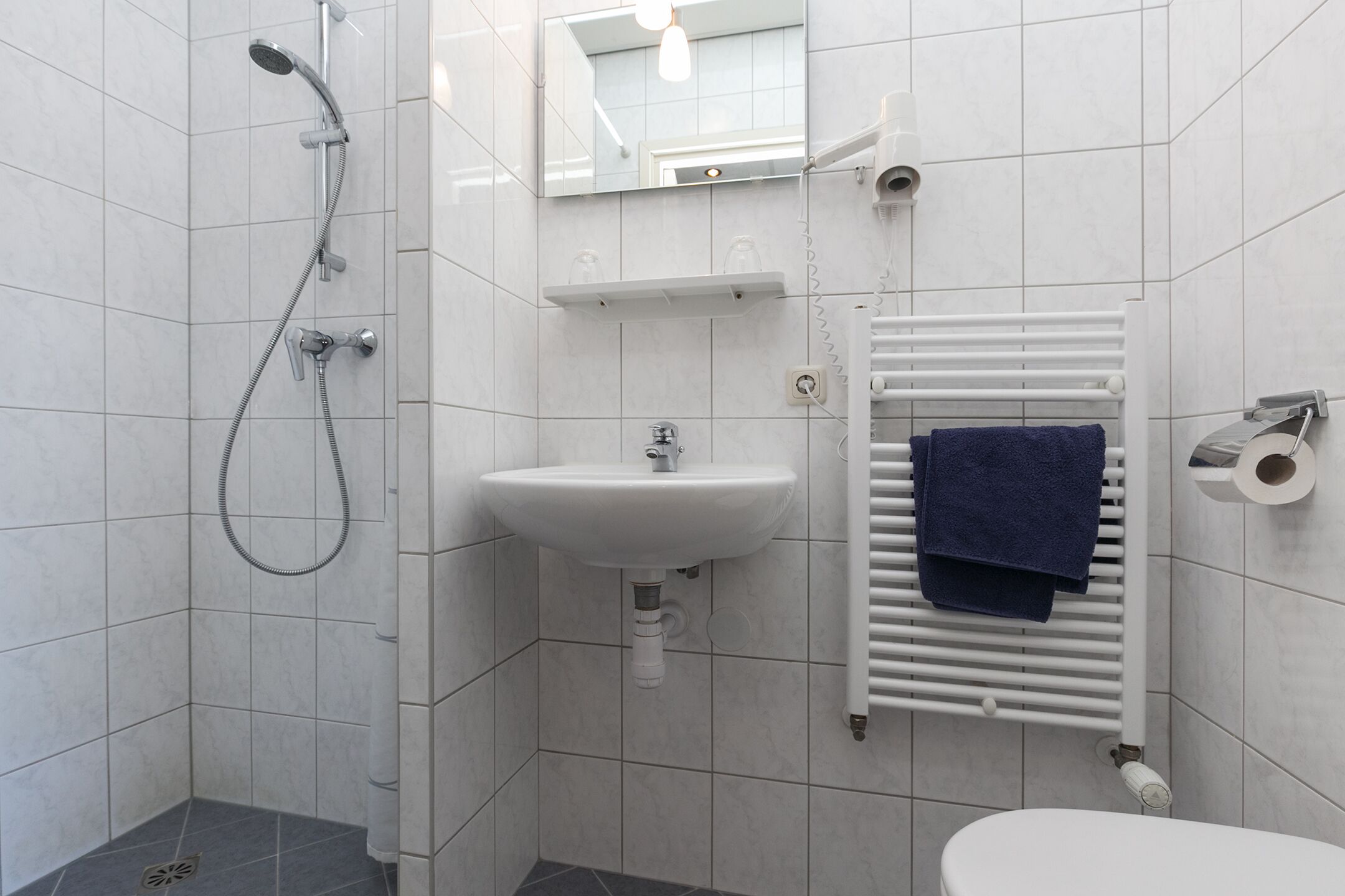 A bathroom with a shower, sink, toilet, and towel rack.