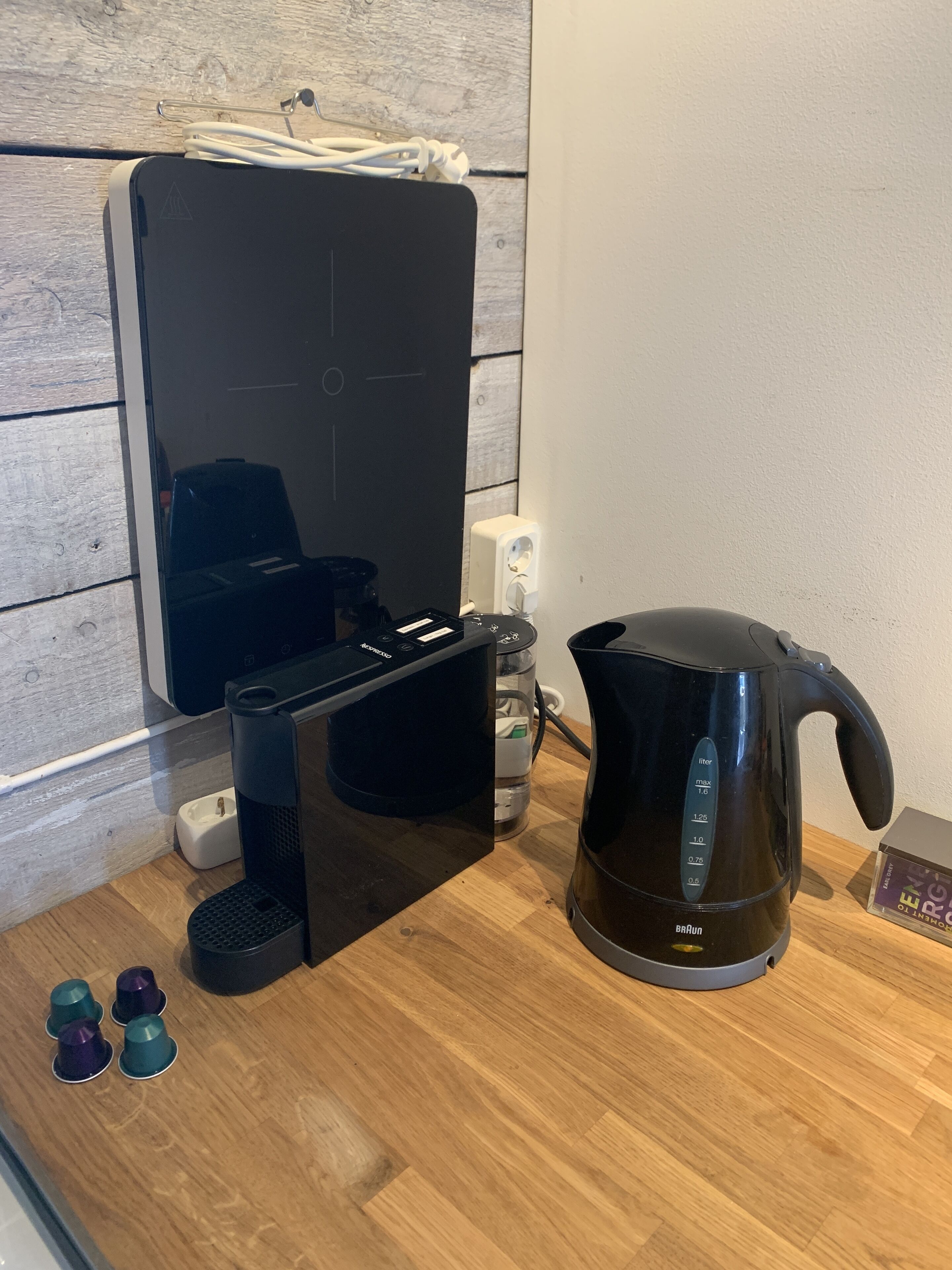 A kitchen with a coffee maker, a kettle, and a water dispenser on a wooden countertop.