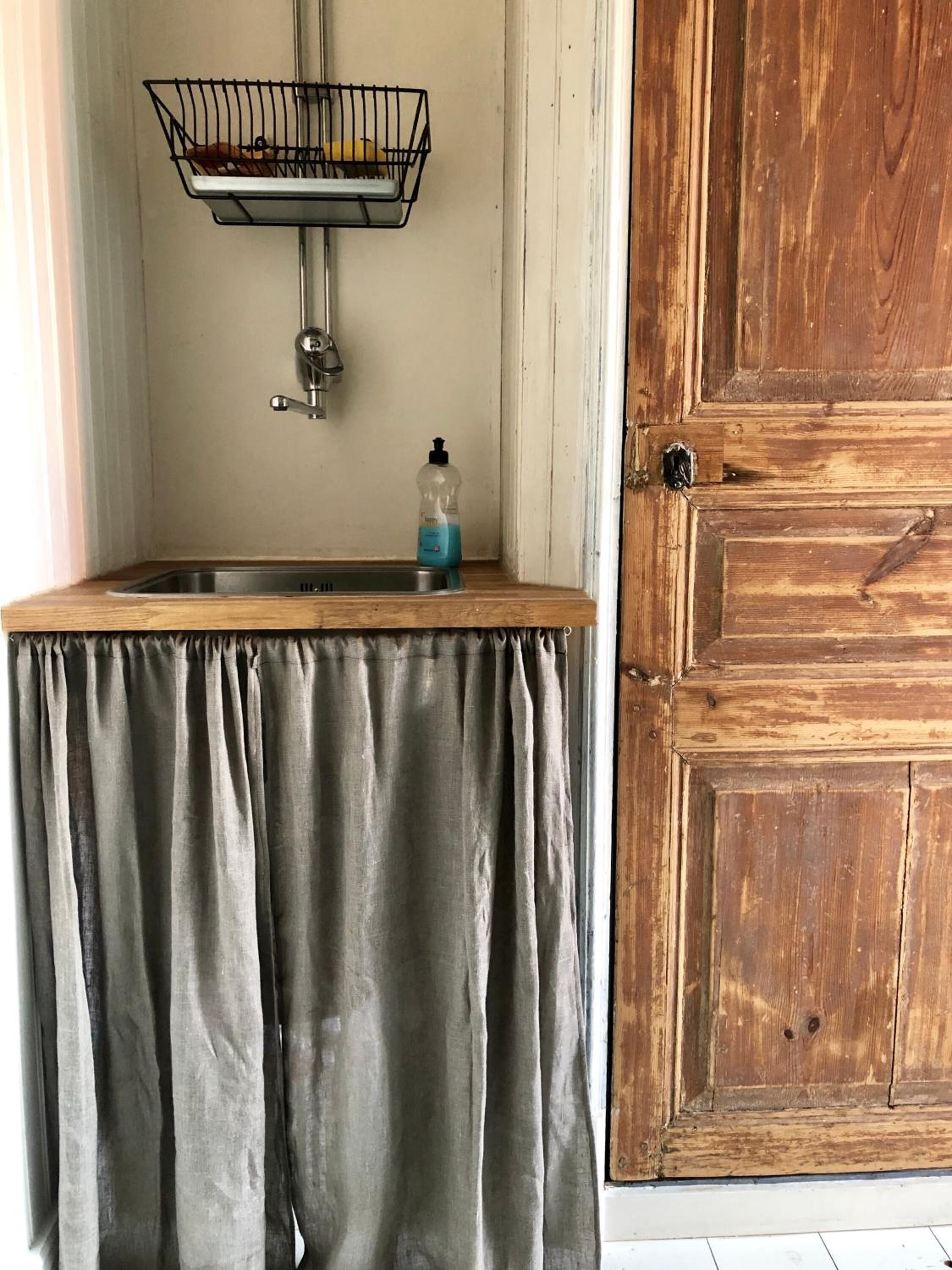 Un coin cuisine comprenant un évier, un panier en métal et une bouteille de liquide vaisselle.