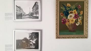 Drie ingekaderde foto’s aan een muur: een zwart-wit straatbeeld, een kleurrijke bloevas, en nog een zwart-wit straatbeeld.