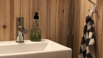 A bathroom with a white sink, a bottle of hand soap, and a towel hanging on a hook.