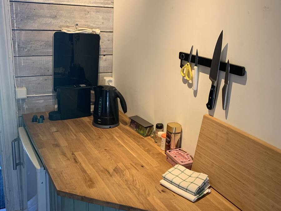 A kitchen with wooden countertops, a kettle, a coffee maker, and a knife rack.