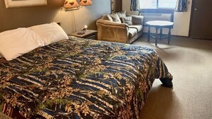 Une chambre d’hôtel avec un grand lit, un canapé, une petite table et une fenêtre avec des rideaux.