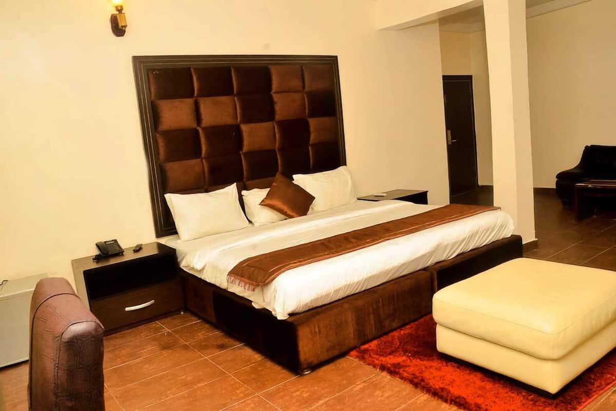 A modern bedroom with a large bed, a nightstand, a chair, and a red rug.