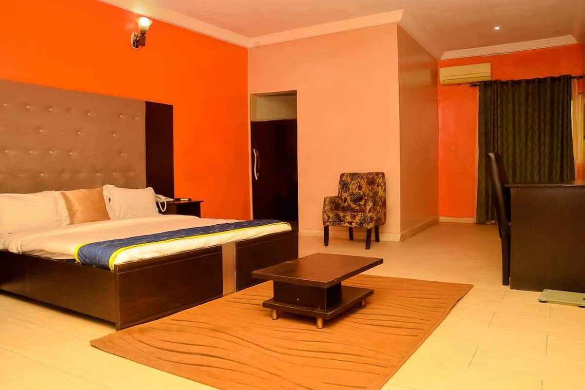 A hotel room with a bed, a small table, a chair, and a desk.