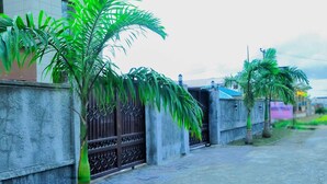A residential street with a concrete wall, metal gate, and palm trees. - Water Ripples Hotel (Lekki)