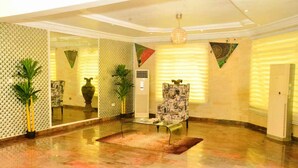 A spacious lobby with a patterned wall, a glass coffee table, a patterned armchair, and a large mirror. - Water Ripples Hotel (Lekki)