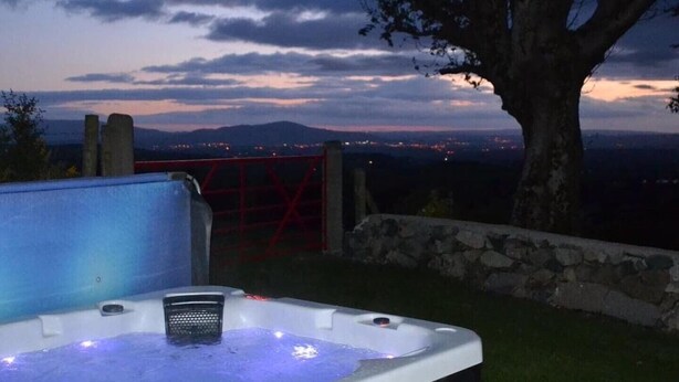 A hot tub with a view of a cityscape at dusk. - Mc Courts Cottage, Mourne Mountains  (HILLTOWN)