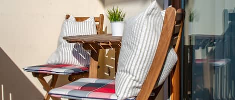 Two wooden chairs with striped cushions and a small potted plant on a tiled patio.