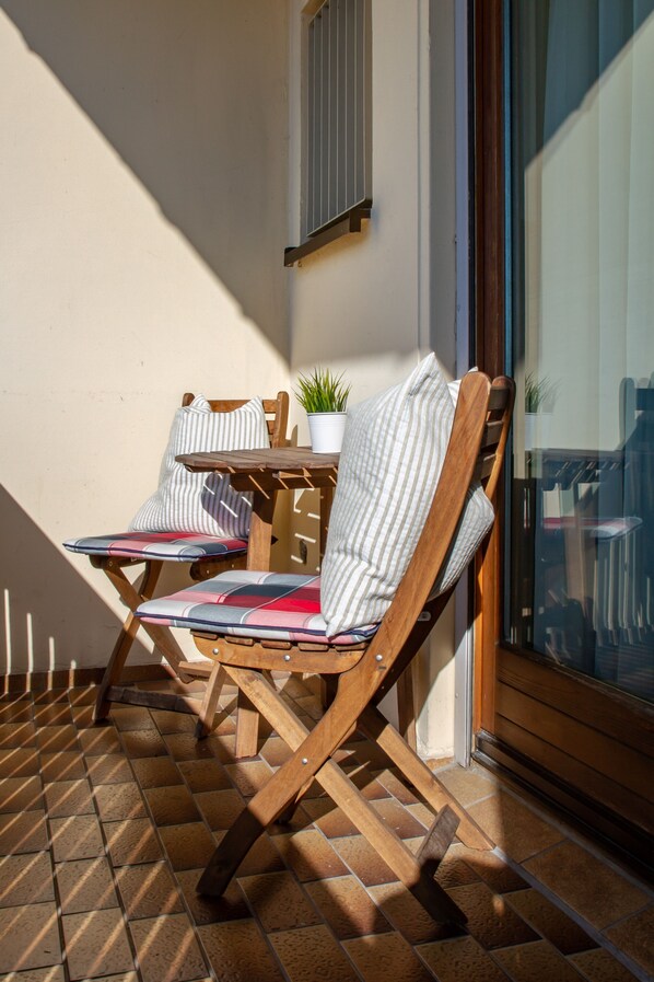 Two wooden chairs with striped cushions and a small potted plant on a tiled patio. - Hotel Restaurant Bastei (Muhldorf am Inn)