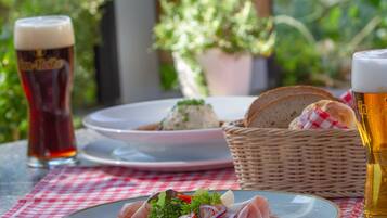 Ein Tisch mit Essen, einem Brotkorb und zwei Biergläsern.