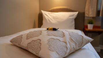 A neatly made bed with a patterned pillow and a small decorative item on top.