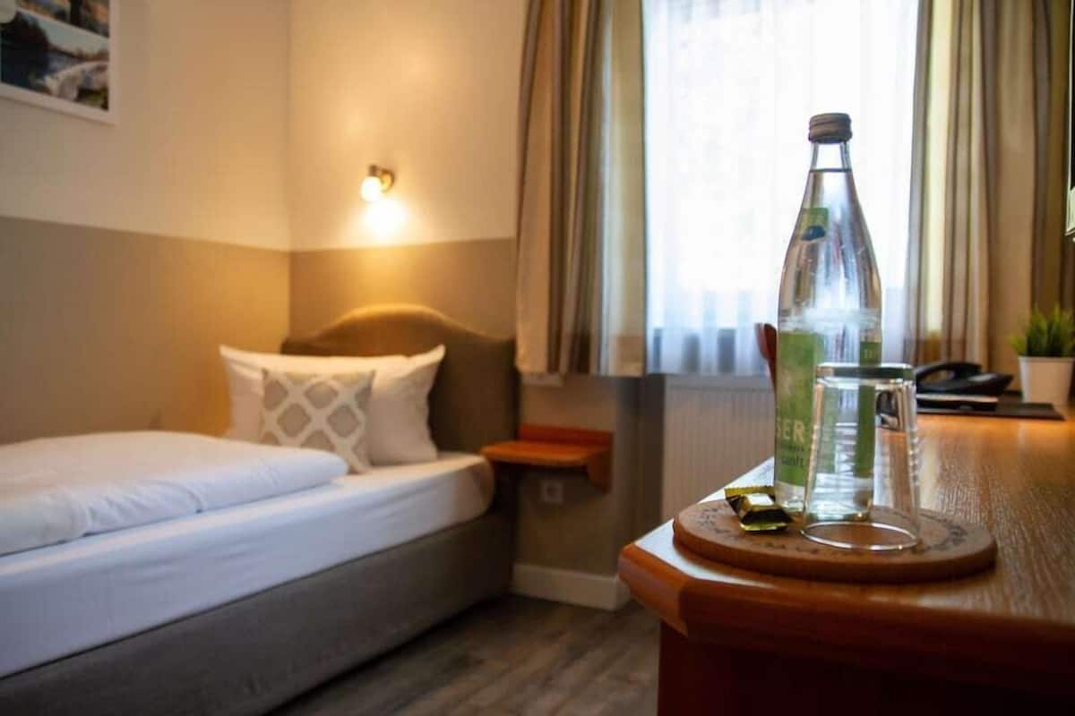 Une chambre d’hôtel avec un lit, une table de chevet, une bouteille et un verre.